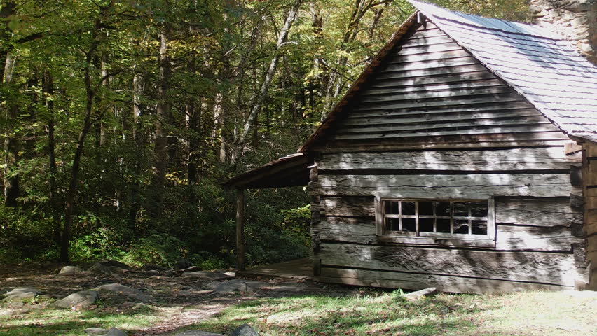 A historic,weathered cabin nestled in the woods of the Great Smoky Mountains in the shadow of autumn trees