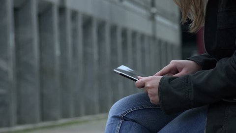 using tablet in the city: young woman with a tablet sitting in urban context Stock Video