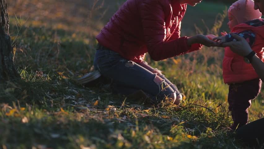 Happy family playing with daughter in the autumn field. Mother kissing baby.