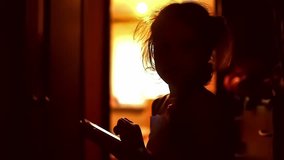 girl  teen looking game smartphone on the Internet in the corridor indoor yellow brown silhouette
