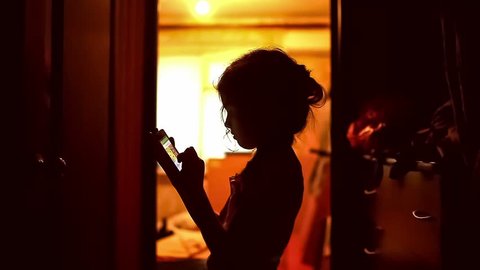 girl teen  looking smartphone game on the Internet in the corridor indoor yellow brown silhouette