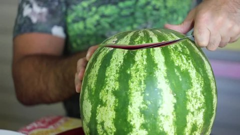 strong male hands cut watermelon with a knife