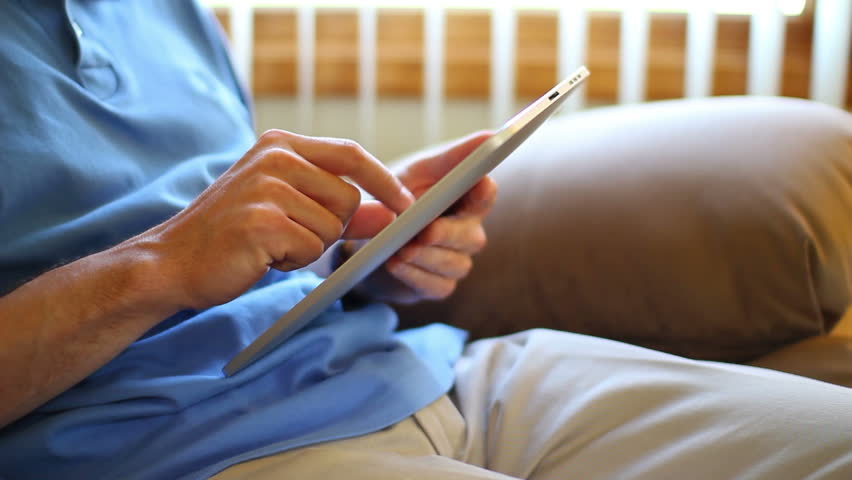 A man sits and uses his touchscreen tablet computer.