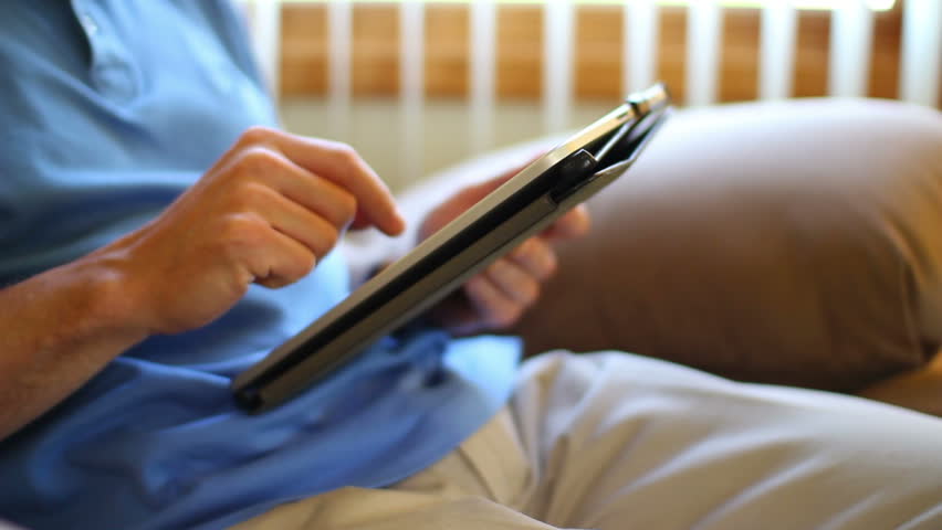 A man sits and uses his touchscreen tablet computer.