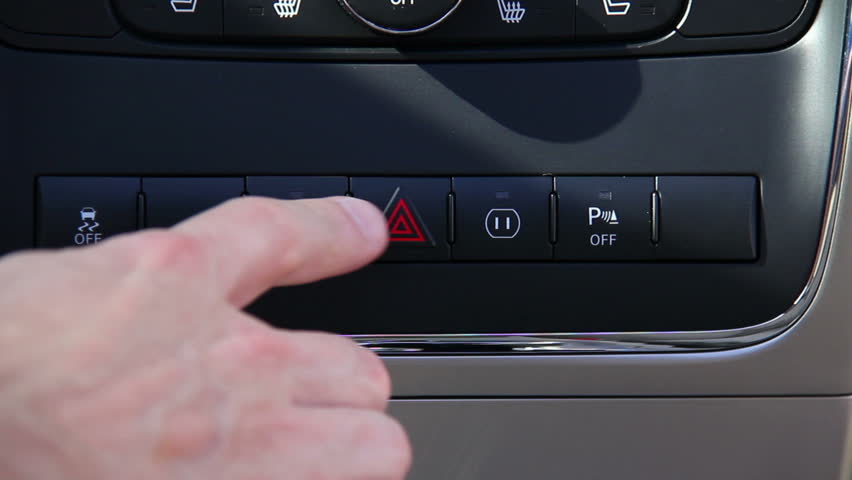 Pushing the hazard lights button on a car's dashboard.