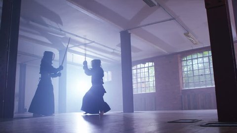 4K Japanese kendo fighters with bamboo swords competing in dark industrial building. Shot on RED Epic.