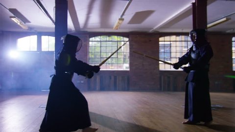 4K Japanese kendo fighters with bamboo swords competing in dark industrial building. Shot on RED Epic.