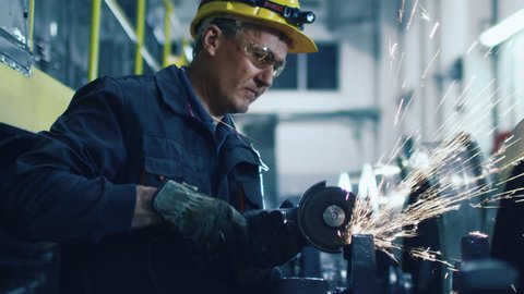 Worker with Angle Grinder does Metalworking in Industrial Environment. Shot on RED Cinema Camera in 4K (UHD).