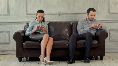 Young couple and ignoring each other looking at smartphones. Professional shot on BMCC with high dynamic range. You can use it e.g in your commercial video, business or office video, reporting