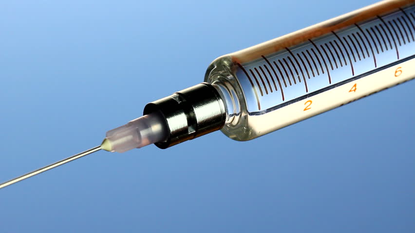 Macro shot of vaccine dispensed from syringe