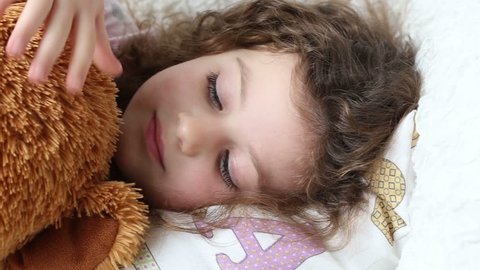 a little girl resting on the couch with a teddy bear, closeup, tracking shot