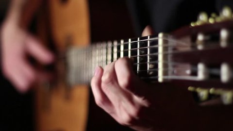 Acoustic, classic, wooden guitar. Brown guitar. Musician plays work. Measured play flamenco. Black background. Fast guitar solo. Six strings. Pluck the strings. Playing with your fingers. Rock'n'roll.