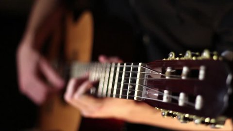 Acoustic, classic, wooden guitar. Brown guitar. Musician plays work. Measured play flamenco. Black background. Fast guitar solo. Six strings. Pluck the strings. Playing with your fingers. Rock'n'roll.