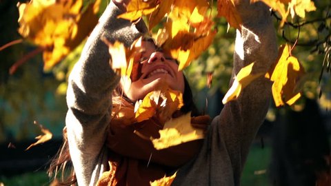 Woman throwing golden leaves in autumn park, slow motion, shot at 240fps
