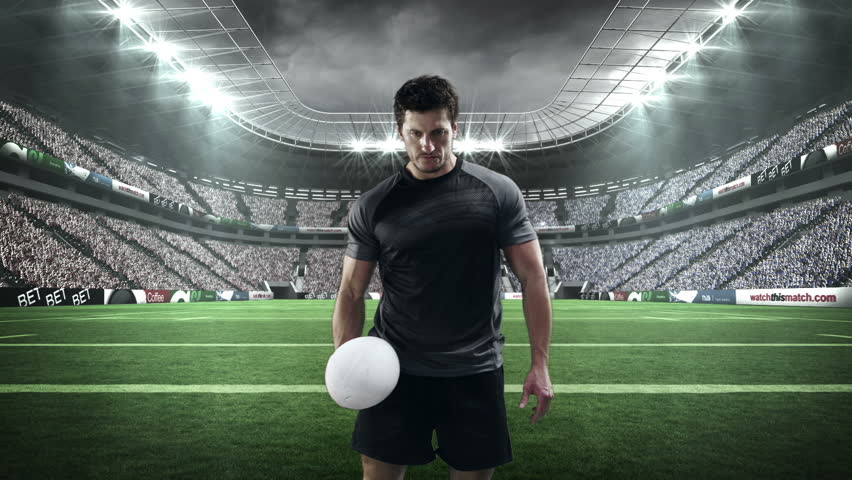 Serious rugby player holding rugby ball in stadium