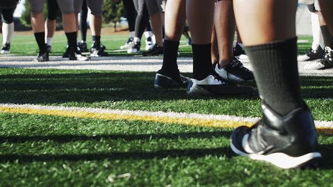 Football players standing around before a game, close up on the cleats