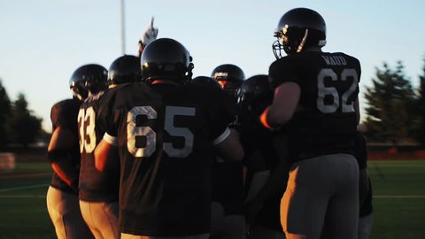 A football team in a huddle gets hyped before a game