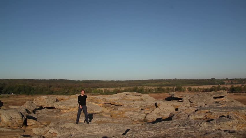 Guy standing on a mountain, on the background sky, and is engaged in taekwondo lessons.