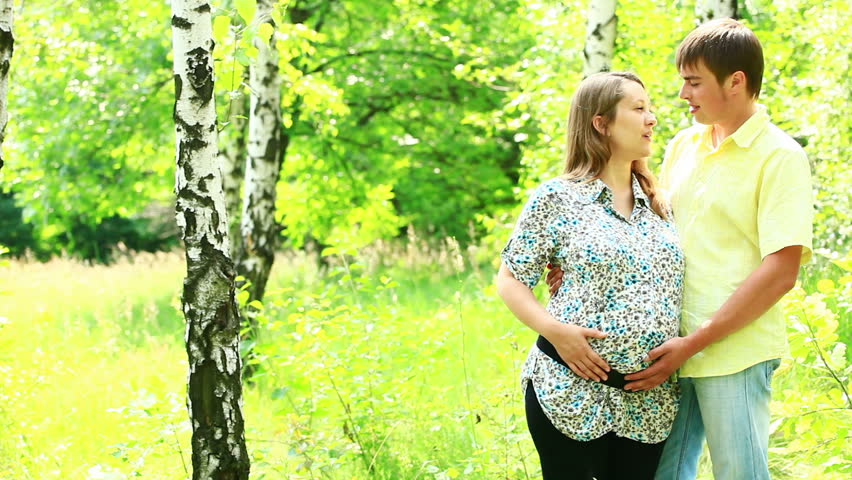 Happy pregnant couple standing in the forest 