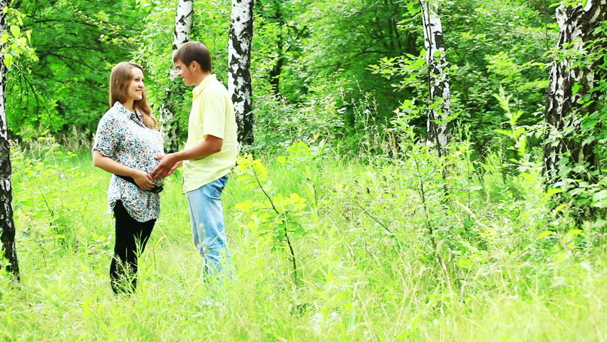 Happy pregnant couple walking in the park 