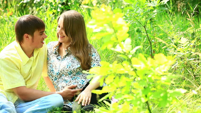 Portrait of pregnant woman couple sitting in grass 