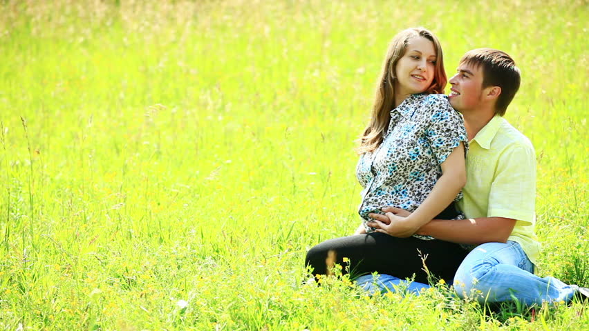 Pregnant couple sitting on the grass 