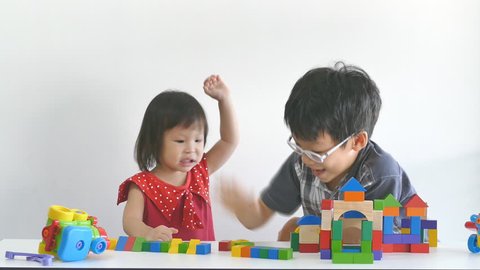 little girl crying and hitting his brother between playing blocks together