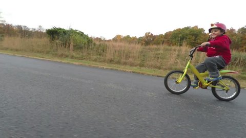 Boy Riding a bicycle on a country Road During Fall Season.
Boy Wearing Bright Red And Yellow Contrasting Colors of Fall.