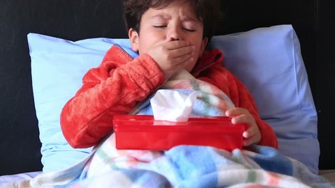 Sick child in bed sneezing