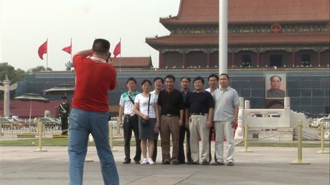 Beijing, China - September 2007: Chinese tourists posing for a group photo in Tiananmen Square, with Tiananmen Gate to Forbidden City in background, Beijing, China.