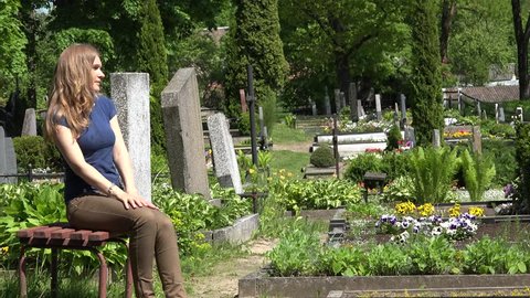young sad woman visit relatives graves in country cemetery. 4K UHD video clip.