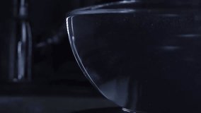 Water from water tap overflowing a glass bowl, slow motion video