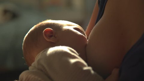 A mother feeds her breast milk and lulls her infant
