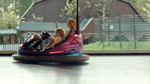 Happy mother with her daughter drive on bumper cars in Amusement park. Shot on BMCC RAW with high dynamic range. You can use it e.g in your video, documentalistic, reporting, family, music video