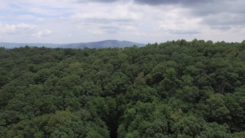 Aerial shot rising over the treetops revealing the Appalachian Mountain Range on a bright day.