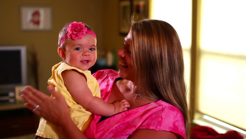 A mother plays with her newborn in her living room.