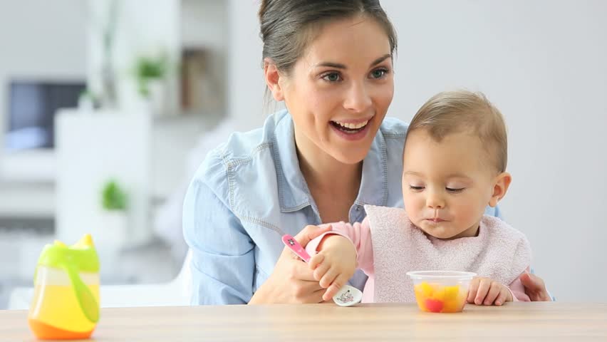 Young Mother Helping Baby Girl Eating: стоковое видео (без лицензионных пла...