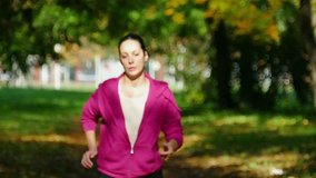 A young woman runs in a beautiful green park in slow motion, The Slow Motion of Running in a Nature, Slow Motion Video Clip