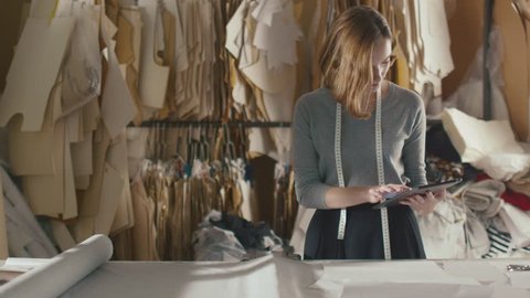 Clothing designer is working with a tablet in a workshop. Shot on RED Cinema Camera in 4K (UHD).