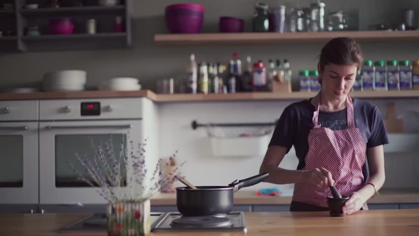 Young girl in apron preparing food in the home kitchen