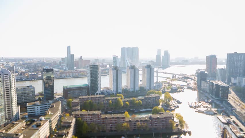 Panning motion tilt shift timelapse on a sunny autumn day w boats moving in and out the harbour in the urban landscape with skyscrapers in the european city, Rotterdam, the Netherlands, October 2015