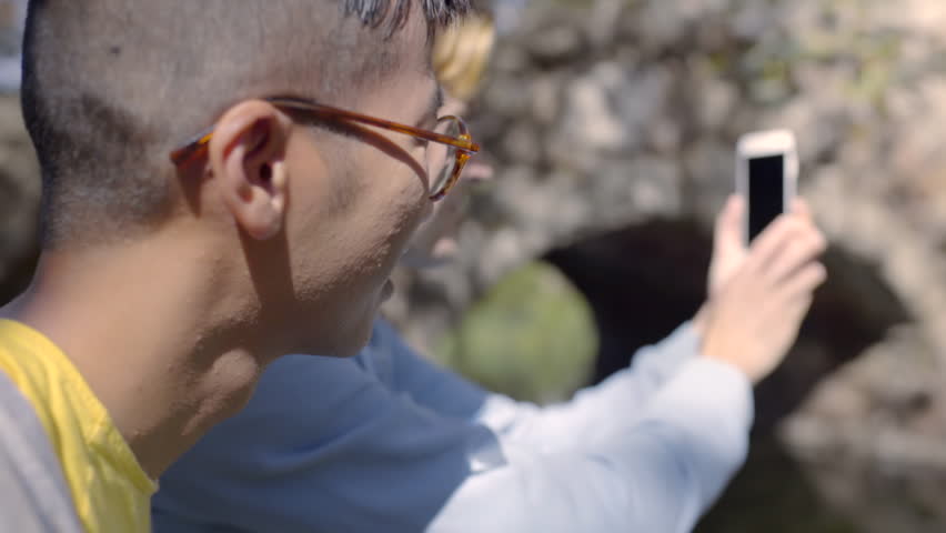 Closeup Of Gay Couple Sitting In Park, Man Takes Panorama Photo With Phone