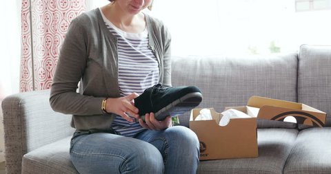 PARIS, FRANCE - Woman unboxing a freshly received box of shoes bought from Crocs online fashion store - by mistake the shoes are for men's
