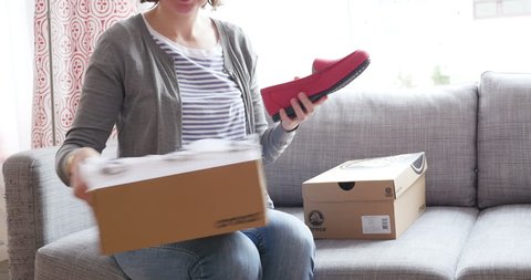 PARIS, FRANCE - Woman unboxing a freshly received box with two smaller boxes bought from Crocs online fashion store 
