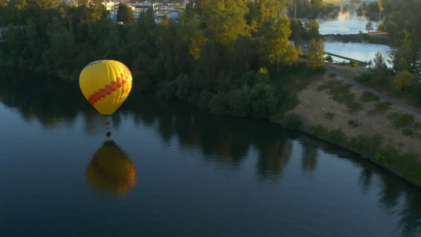 Hot air balloon floats right on top of a river 
