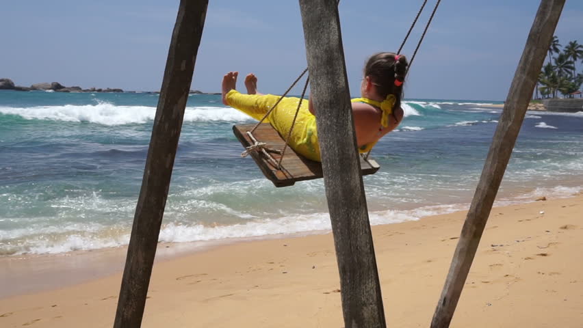 little girl on a swing at the beach near the sea