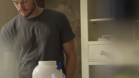 Slow motion clip of a young man making a protein shake at home