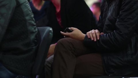 A man sitting at a concert with the phone