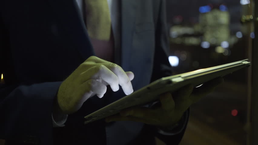 Business male on digital tablet in evening at business district
