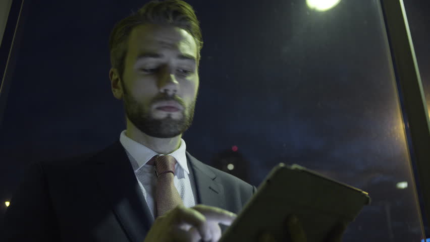 Business male on digital tablet in evening at business district